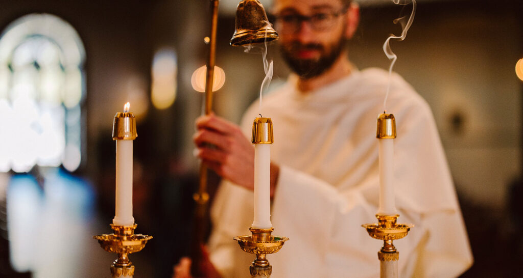 a priest lighting three candles