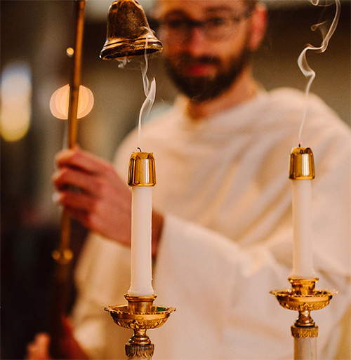 A priest extinquishing candles