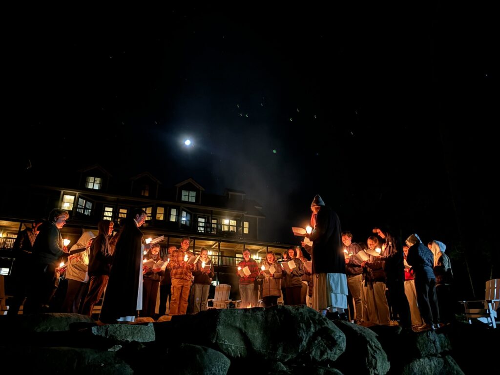 Students holding candles circle around a fire