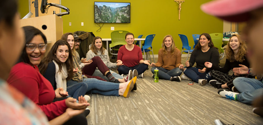 Students seated cross-legged on the floor in a classroom activity