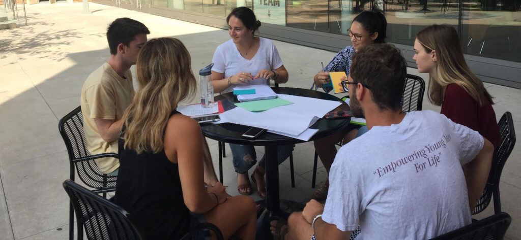 Students seated at a table talking with each other
