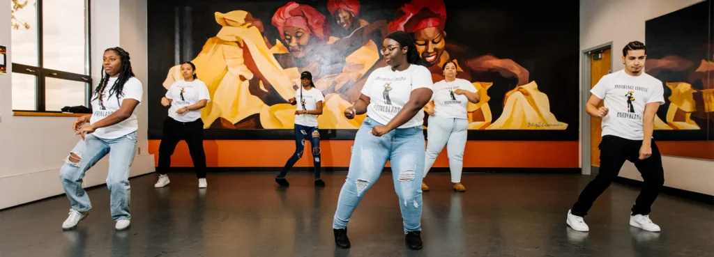 Several students dancing in front of colorful murals